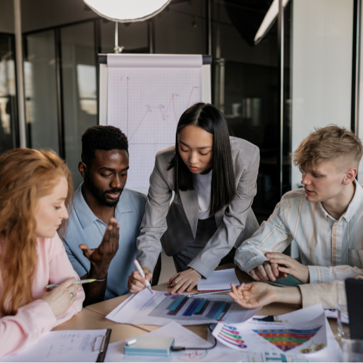 Group of people discussing documents around a table in an office setting