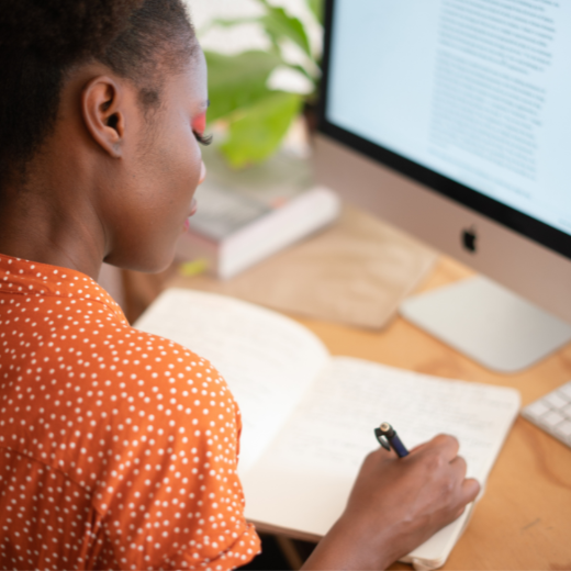 Person working at a desk with a computer and notebook